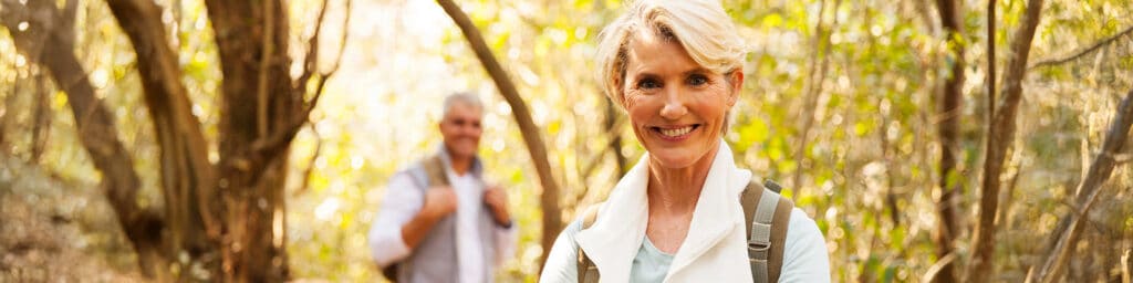 happy mid age woman hiking with husband in forest